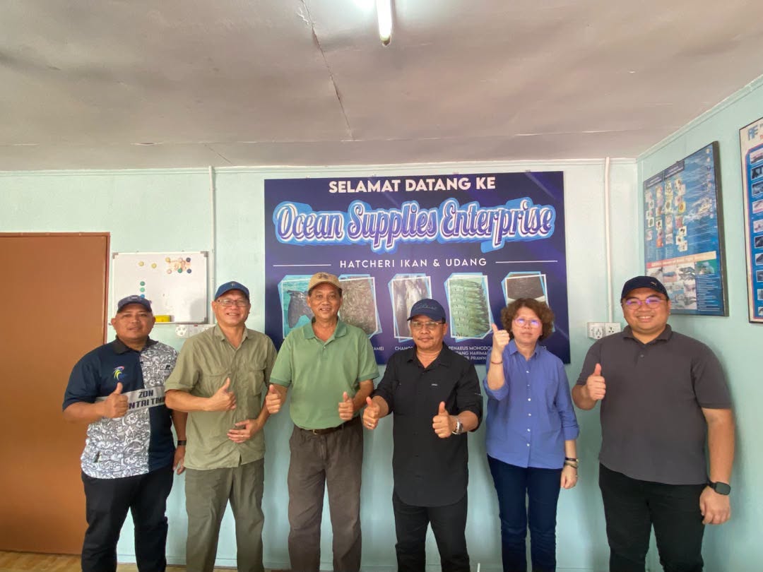 Pengurus Besar Ko-Nelayan, YBhg. Datuk Hj. Yusof Hj. Ag. Besar bersama delegasi Ko-Nelayan dan Jabatan Perikanan Sabah bergambar kenangan di hadapan banner Ocean Supplies Enterprise, hatceri ikan dan udang